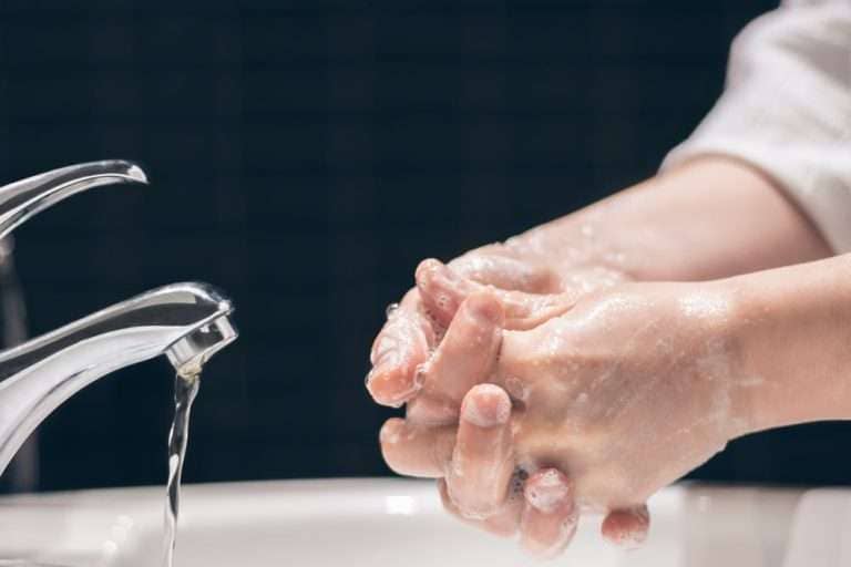 Person washing hands at sink with water filtered by Indy Soft Water