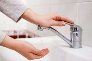 hands turning on the sink faucet