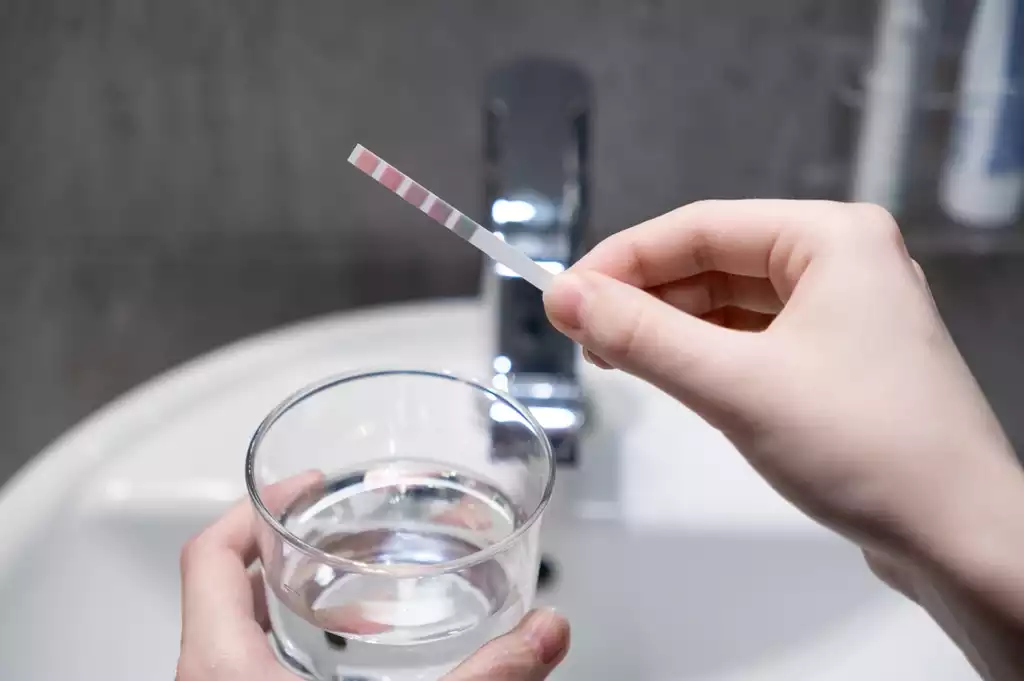 Water quality test strip checking chlorine levels in tap water