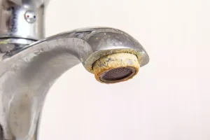 A water faucet for a kitchen sink, with calcified metals around the rim of the aerator due to hard water.
